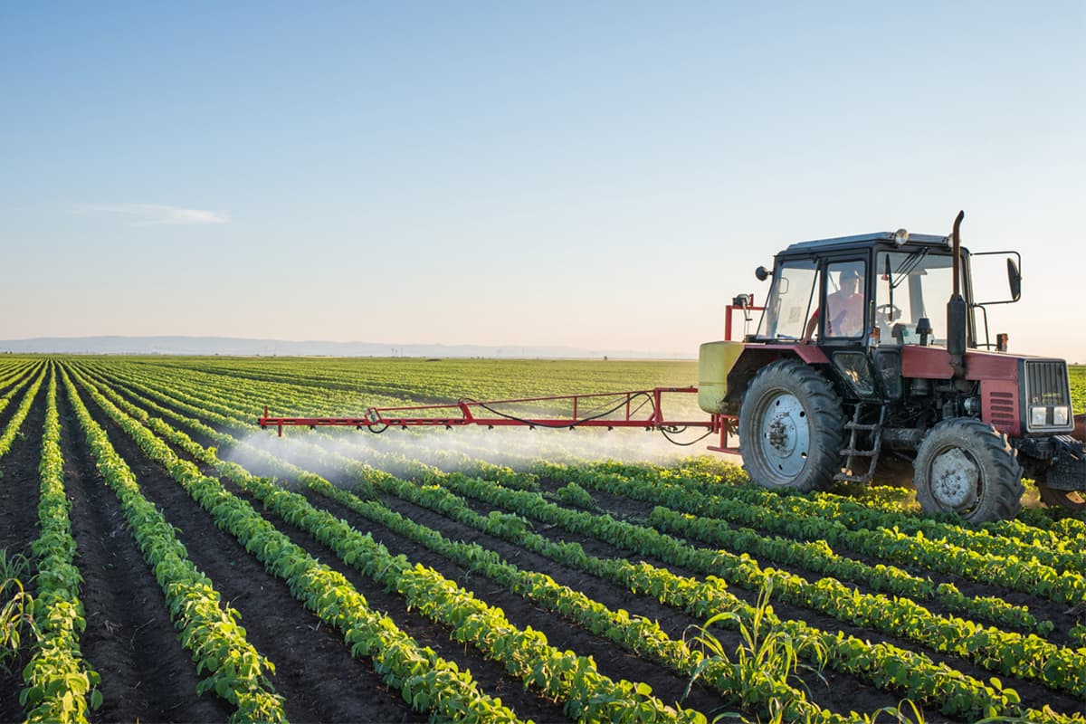 Tractor spraying field with presiticdg